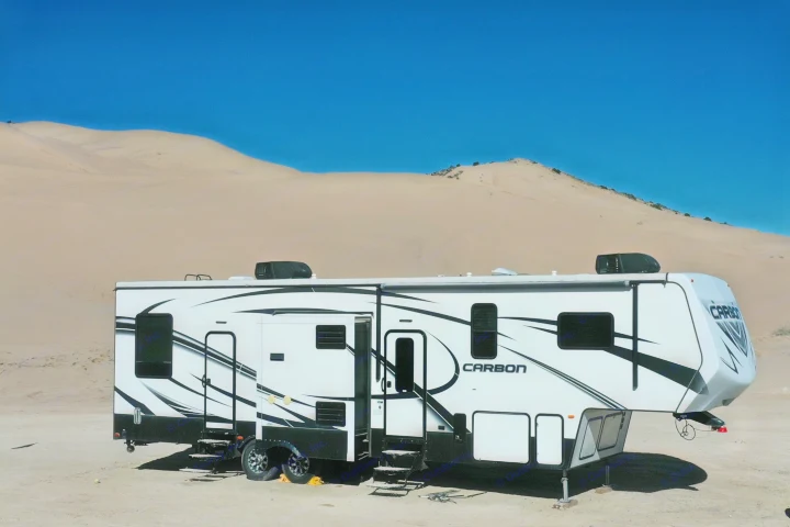 This Carbon fifth-wheel RV rental is perfectly set up for adventure among vast desert sand dunes under a clear sky.. Keystone RV Carbon Toy Hauler 2015