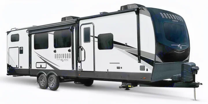 White and black Rockwood travel trailer, an ideal RV rental. This modern recreational vehicle features windows, a door, and a front hitch.. Forest River Rockwood 2025