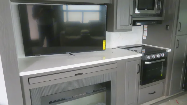 RV rental: Modern kitchen and entertainment area with TV, fireplace, stovetop, oven, and microwave.. Forest River Rockwood 2025