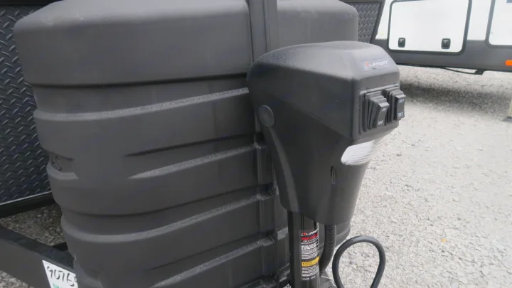 Close-up of an RV's black propane tank cover and Lippert power tongue jack with controls, crucial for any rv rental setup.. Forest River Rockwood 2025