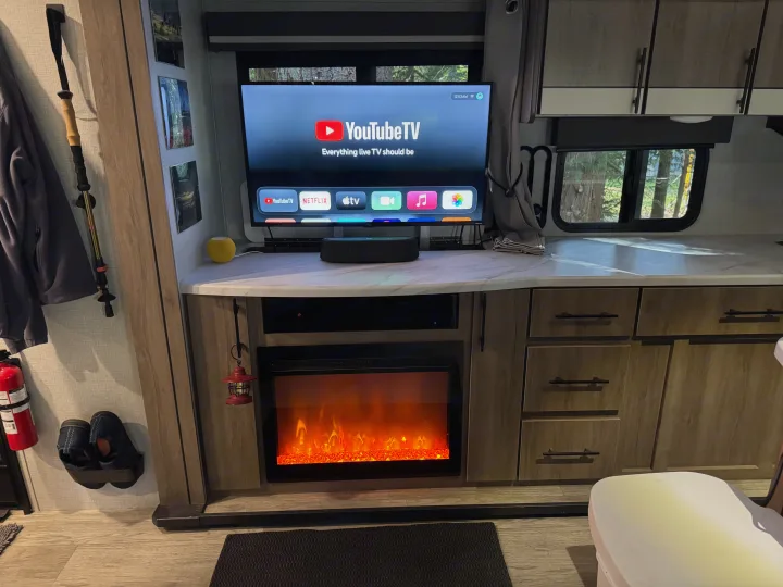 Relax in this RV rental's living area with a smart TV displaying YouTube TV apps, an electric fireplace, and speakers.. Grand Design Imagine 2023