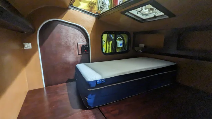 Cozy RV rental cabin interior featuring a comfortable bed, compact design, and overhead ventilation.. Custom Blu Paw 2024