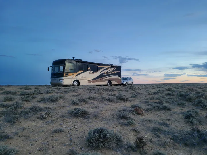 Berkshire RV rental with towed car, parked in vast, dry landscape at twilight.. Forest River Berkshire 390-Bunkhouse 2012