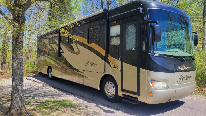 A large dark and gold Berkshire RV rental parked at a shady campsite, ready for your next camping trip.. Forest River Berkshire 390-Bunkhouse 2012