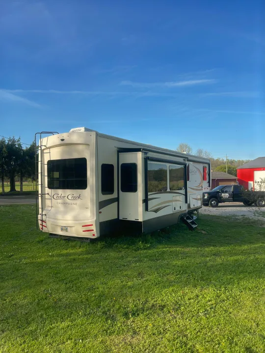 Fifth wheel RV rental, a Cedar Creek Champagne model, parked on green grass with its slides out, ready for adventure.. Cedar Creek Champagne 2019