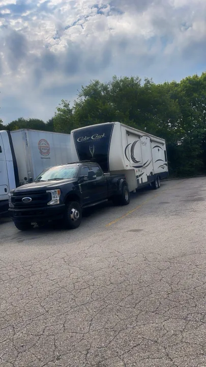 A black Ford Super Duty dually truck towing a large Cedar Creek fifth-wheel RV. Perfect for an RV rental getaway.. Cedar Creek Champagne 2019