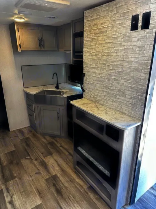 This modern rv rental boasts a full kitchen with stainless sink and microwave, plus a built-in electric fireplace. Ready for travel!. Dutchmen Coleman Lantern 2022