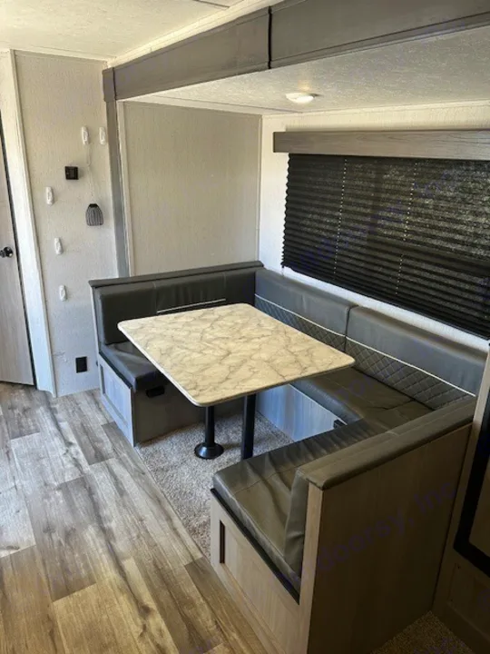 Inside an RV rental, a cozy U-shaped dinette with dark cushions & marble-look table offers a comfortable space.. Dutchmen Coleman Lantern 2022