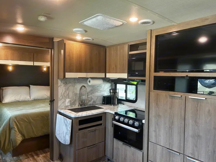 Inside your rv rental: a cozy bedroom, fully-equipped kitchen with stove & microwave, and smart storage.. Grand Design Imagine 2022