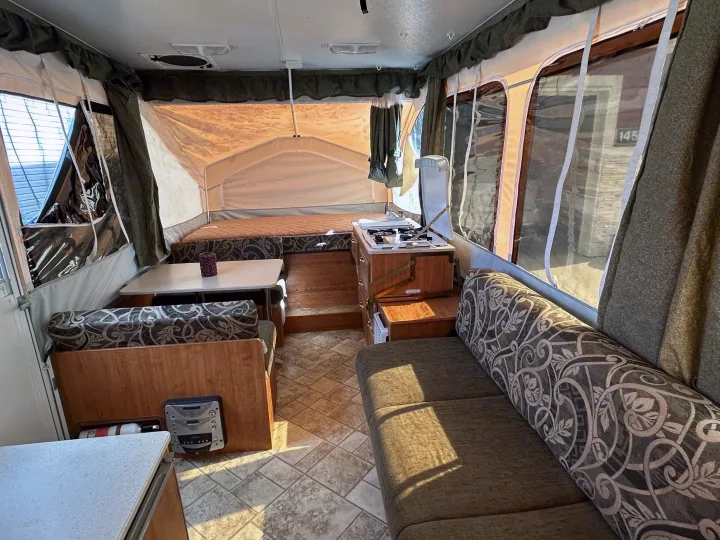 Cozy interior of an RV rental pop-up camper, featuring a dinette, bed, and kitchen. Ideal for camping getaways.. Forest River Flagstaff 2008