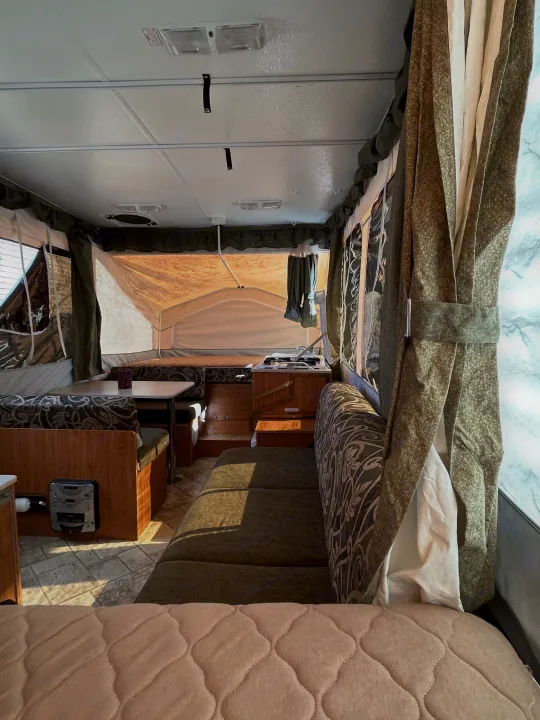 Spacious pop-up camper RV rental interior, showing a dinette, sleeping areas, and kitchen.. Forest River Flagstaff 2008