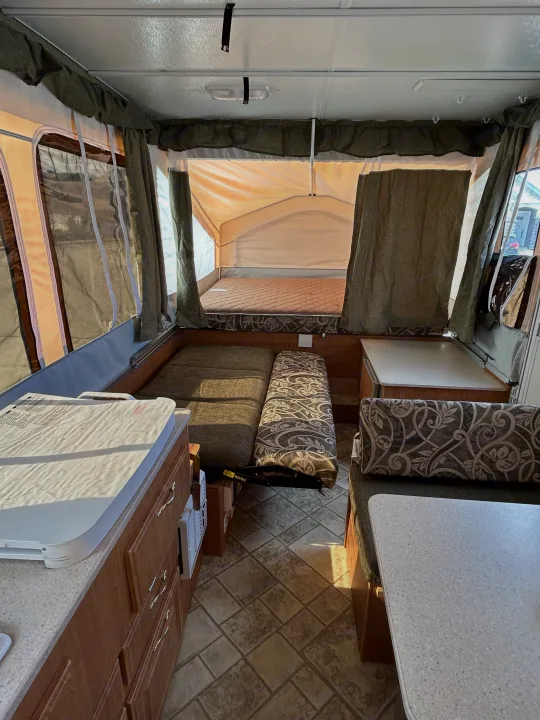 Interior of a pop-up RV rental, highlighting beds, dinette, and compact kitchen. Perfect for camping trips.. Forest River Flagstaff 2008