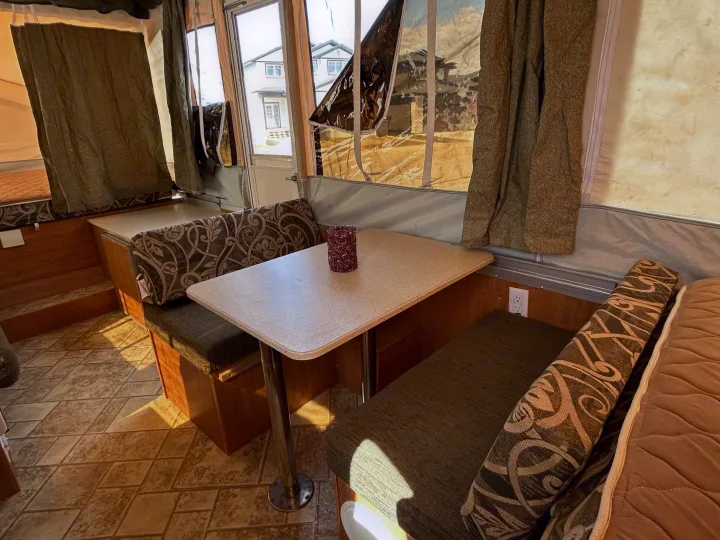 Step inside this cozy RV rental's dinette area, featuring comfortable seating, a table, and bright windows.. Forest River Flagstaff 2008
