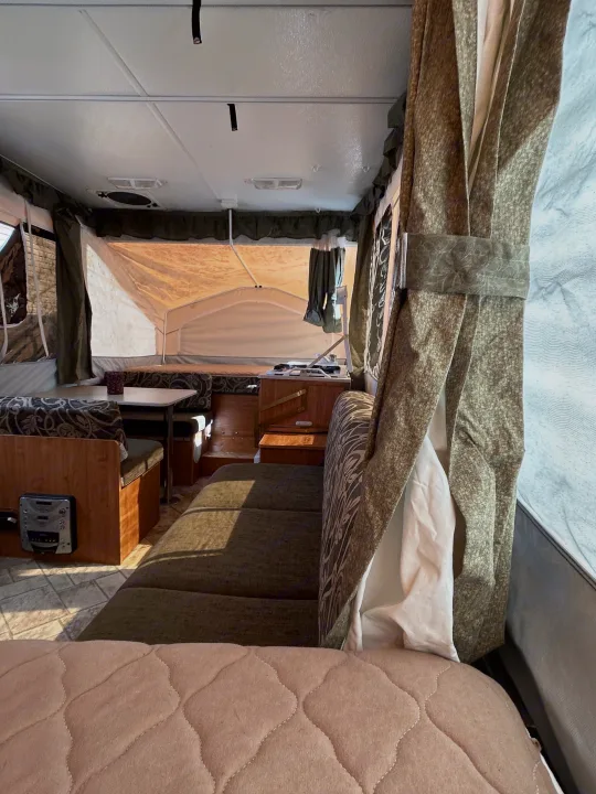 Inside an RV rental, showing a pop-up camper's interior with dinette, kitchen, and sleeping space.. Forest River Flagstaff 2008