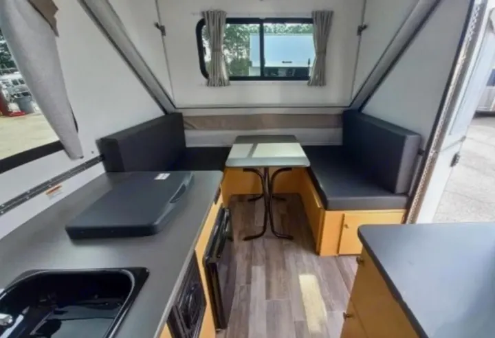 RV rental: A-frame camper interior with wood-look floor, kitchenette (sink/stove), and dinette.. A-Liner Ranger 2025