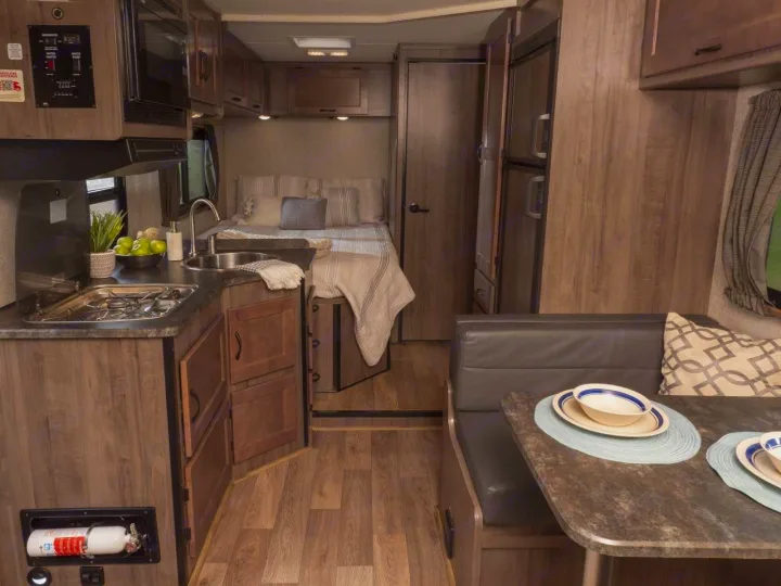 RV rental interior: practical kitchen, comfortable bed, and dining booth with wood-grain styling.. Winnebago Minnie Winnie 2020