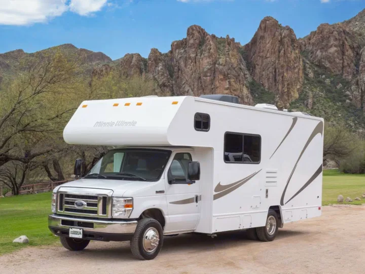 White Class C RV rental (Minnie Winnie) parked against rugged mountains. Perfect for scenic outdoor adventures.. Winnebago Minnie Winnie 2020