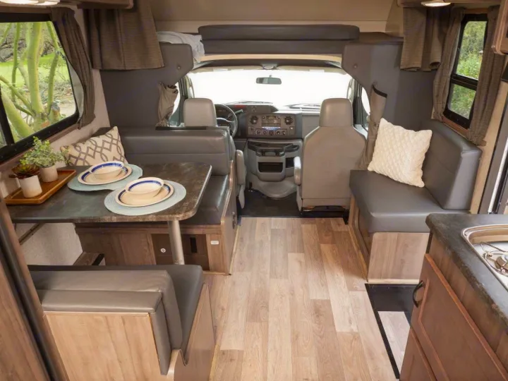 RV rental interior: A full view of a motorhome's living area with a dinette, kitchen sink, and front cab.. Winnebago Minnie Winnie 2020