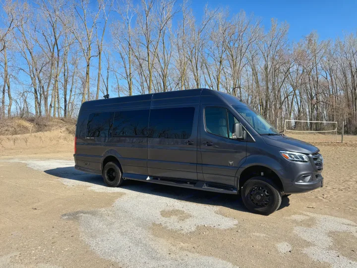Dark grey Sprinter van, perfect for RV rental adventures, parked outdoors near a sand volleyball court with bare trees.. Mercedes-Benz Sprinter 2026