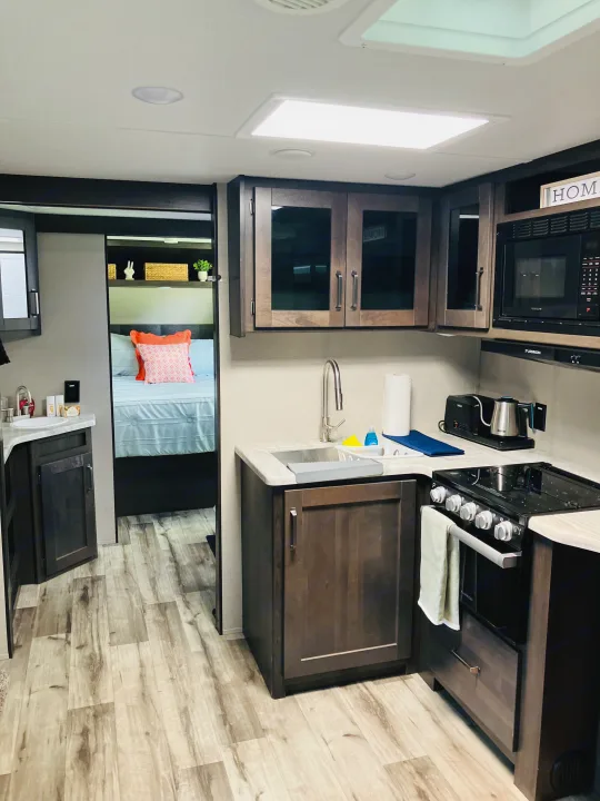 Spacious RV rental with a modern kitchen, full amenities, and a peek into the cozy bedroom area.. Grand Design 265BH 2023