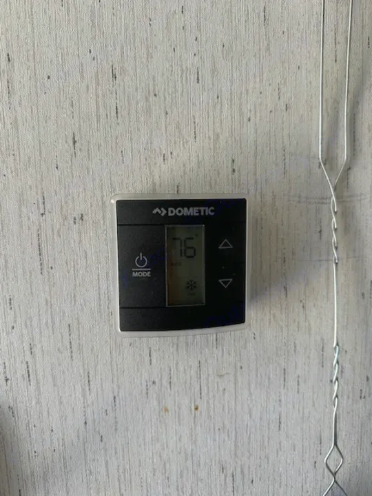 Dometic RV thermostat shows 76° on a light wall. Essential climate control for an rv rental for comfort.. Dutchmen Coleman Lantern 2022