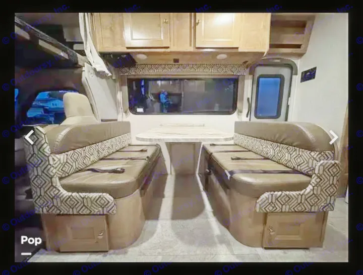 RV rental interior: inviting dinette with patterned benches & table, overhead storage, and exit door. Ready for adventures!. Coachman Leprechaun 2020