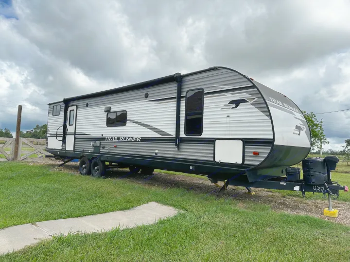 Modern gray 'Trail Runner' travel trailer. An inviting RV rental parked on grass under a cloudy sky.. 5sfeb3729me459252 31DB 2021