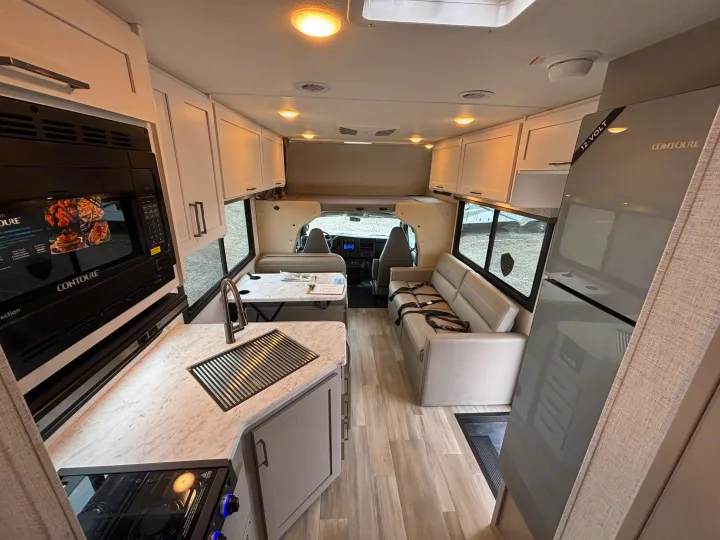 Spacious RV rental interior with a bright kitchen, microwave, dinette, sofa, and cab-over bed for travel comfort.. Thor Motor Coach Four Winds 2026