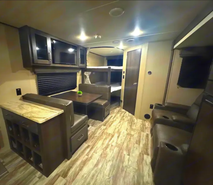 RV rental interior: spacious living area featuring dinette, bunk beds, recliners, TV, and ample storage for comfort.. Grand Design Transcend Xplor 2022