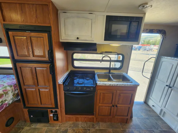 Explore this RV rental's full kitchen with Dometic fridge, Suburban stove, Magic Chef microwave, and double sink.. Forest River Rockwood Mini Lite 2014