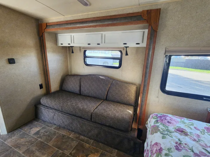 Comfortable RV rental interior with a sofa bed, overhead storage, and a cozy floral bed, ideal for travel.. Forest River Rockwood Mini Lite 2014