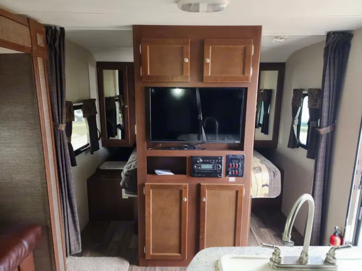 Explore this RV rental's interior: central media console, two cozy sleeping quarters, and a functional kitchen sink.. Keystone RV Bullet Ultra Lite 2015