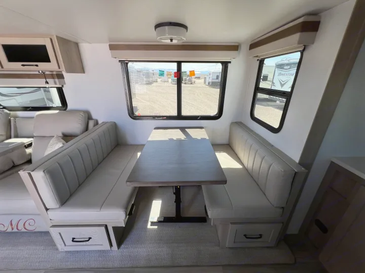 Modern RV rental interior: Light-filled dinette with comfortable booth seating, adjustable table, and storage drawers.. Forest River Rockwood Ultra Lite 2024