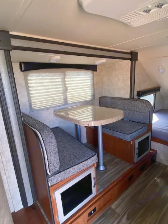 Step inside this RV rental! Features a comfortable dinette with two benches, a table, and integrated storage. Bright camper interior.. Travel Lite Falcon 2018