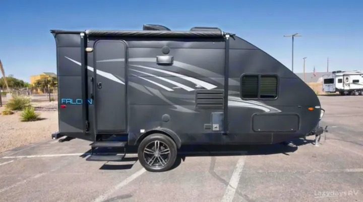 Sleek black Falcon travel trailer RV rental, featuring modern graphics & design, parked on asphalt.. Travel Lite Falcon 2018