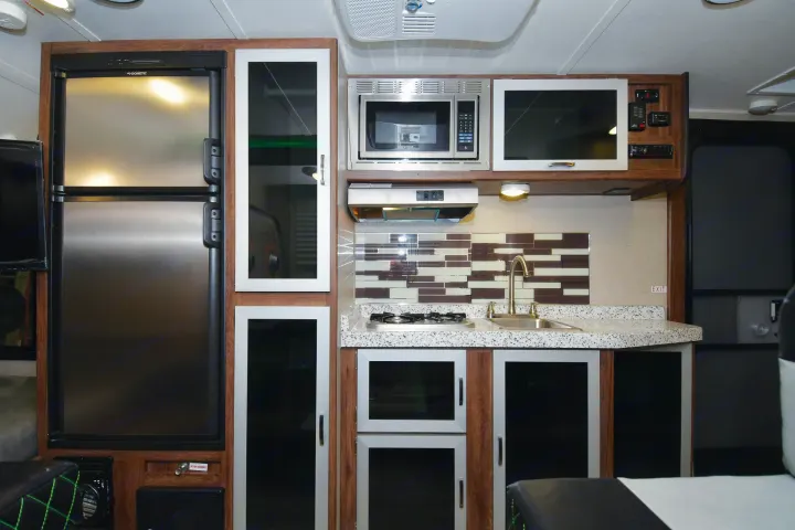RV rental kitchen with fridge, microwave, stovetop, sink, and stylish cabinets. A fully equipped galley.. Travel Lite Falcon 2018