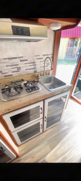 Inside an **rv rental**: a modern, compact kitchen featuring a two-burner stove, sink, and storage cabinets.. Travel Lite Falcon 2018