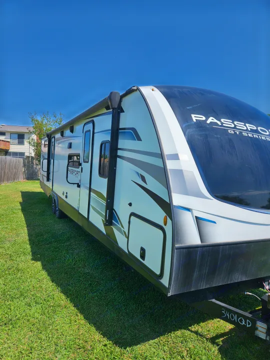 Discover this spacious white Passport GT Series travel trailer. Ideal for your next rv rental trip, parked on sunny grass.. Keystone RV Passport GT 2022