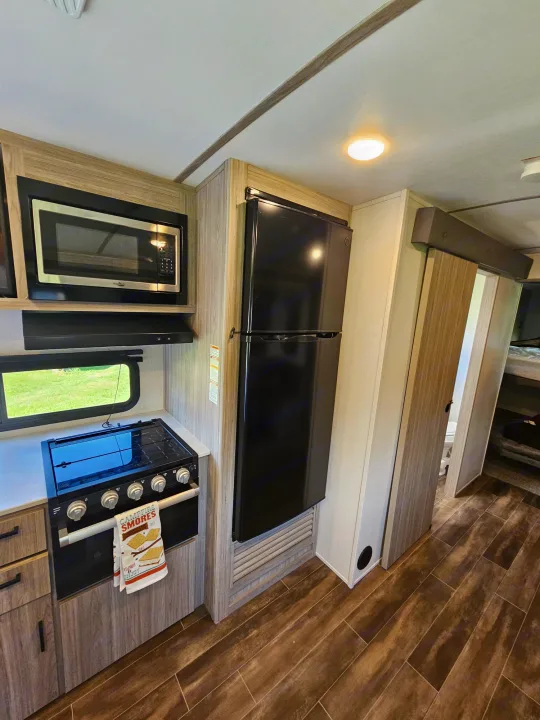 This RV rental features a modern kitchen area with a microwave, stove/oven, and full-size fridge.. Keystone RV Passport GT 2022