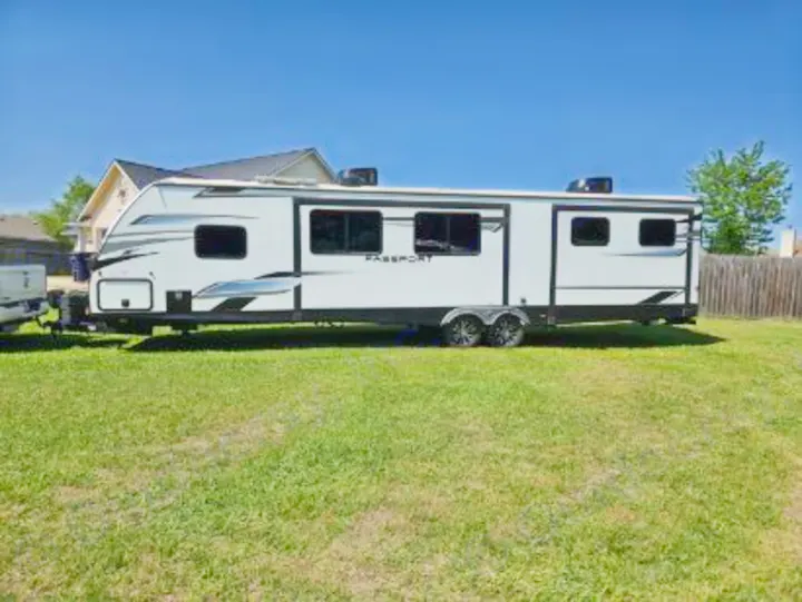 Bright white Passport travel trailer on a green lawn. This modern RV rental offers comfort for your next adventure!. Keystone RV Passport GT 2022