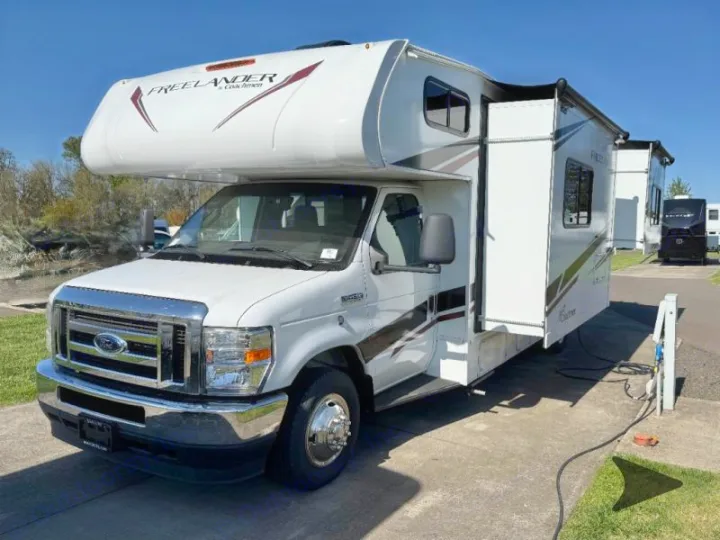White Coachmen Freelander RV rental at an RV park, showing its slide-out extended and power hookups.. Coachmen RV Freelander 26DS 2023