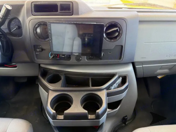 RV rental interior: Dashboard with digital screen, air vents, and center console featuring cup holders and storage.. Coachmen RV Freelander 26DS 2023