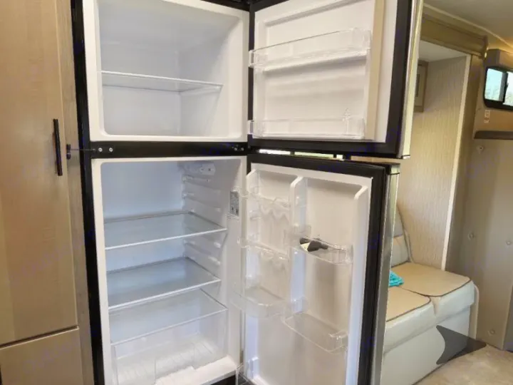 Empty, clean RV rental fridge/freezer, with transparent shelves, ready for your trip's groceries.. Coachmen RV Freelander 26DS 2023