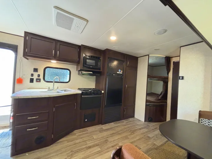 RV rental interior showing a kitchen with appliances, dining area, and rear bunk beds for travelers.. Jayco Jay Flight 2020