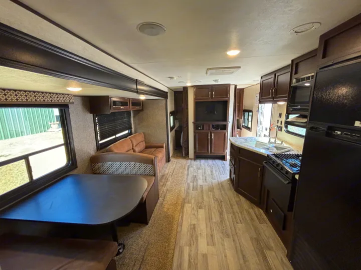 Spacious RV rental interior with a fully equipped kitchen, comfortable dinette, sofa, and rich dark wood cabinets.. Jayco Jay Flight 2020