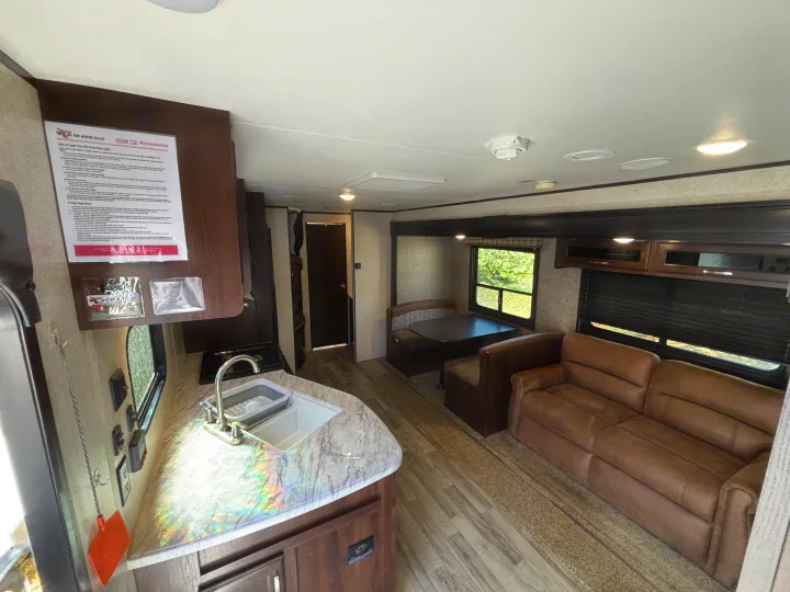 Explore this bright rv rental interior, featuring a full kitchen with sink, a cozy dinette booth, and a comfy sofa.. Jayco Jay Flight 2020