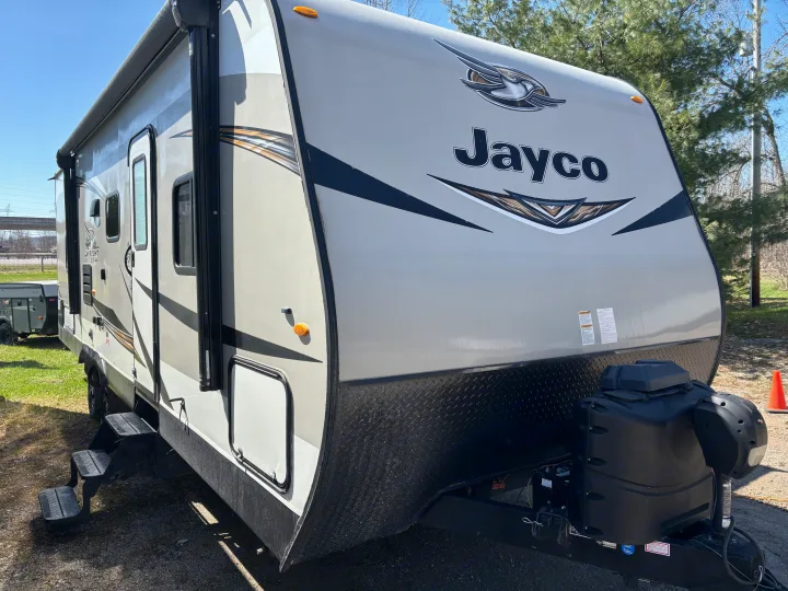 Modern Jayco travel trailer available for rv rental, showing its beige exterior, power jack, and extended steps.. Jayco Jay Flight 2020