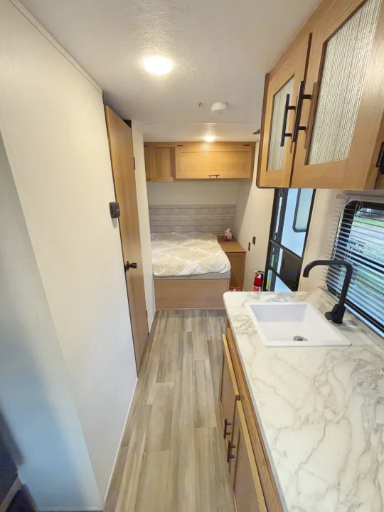 RV rental: Bright interior featuring a compact kitchen with sink and marble-look counter, plus a cozy bedroom area.. Avenger 16RD 2024