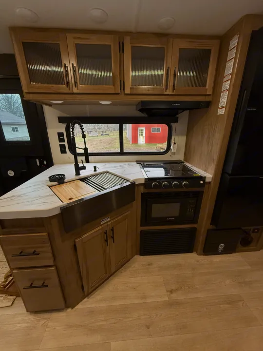 Modern RV rental kitchen: light wood cabinets, large sink, stovetop, microwave, fridge, and ample counter space for road trips.. Forest River Cherokee Grey Wolf 26DBH 2025