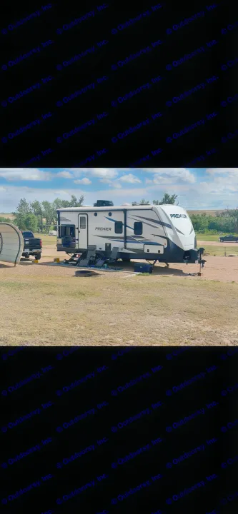 Premier RV rental set up at a scenic campsite with a truck, chairs, and fire pit under a blue sky.. Keystone RV Bullet Premier Ultra Lite 2022